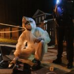 Enquêteur pensif face à un tableau de preuves dans un bureau sombre de police