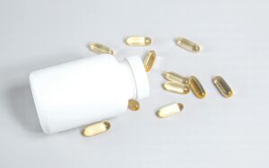 Capsules dorées d'huile de foie de morue posées sur une surface en bois naturel