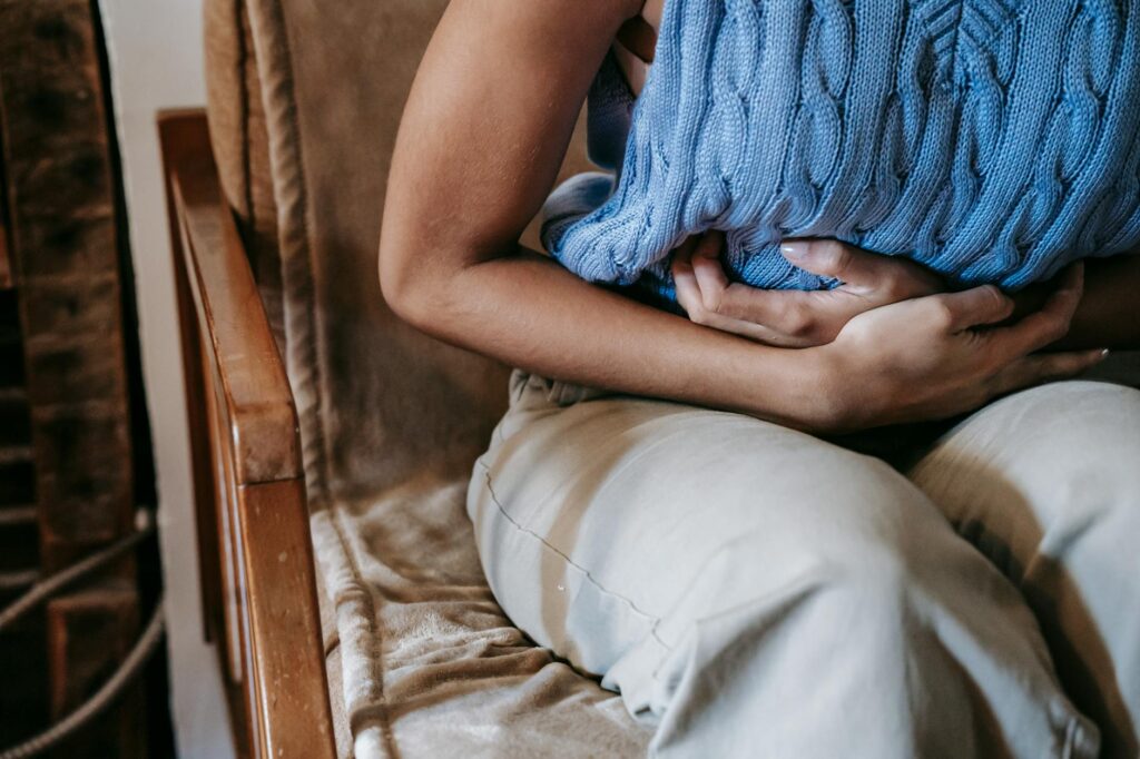 femme allongée sur un canapé avec bouillotte sur le ventre, douleur menstruelle