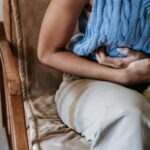 femme allongée sur un canapé avec bouillotte sur le ventre, douleur menstruelle