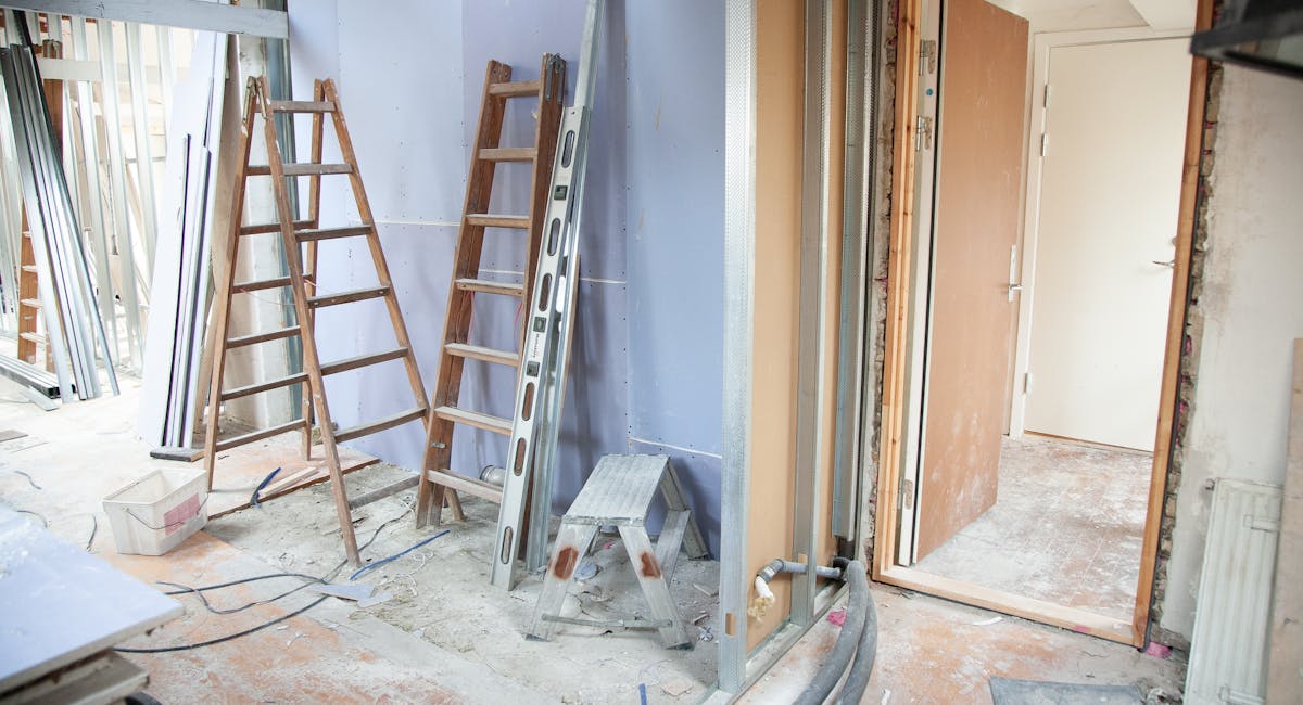 Technicien inspectant l'isolation d'un mur intérieur avec thermomètre infrarouge