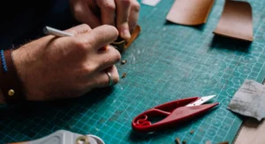 Couper du verre sans le casser : 5 techniques que les vitrriers professionnels cachent aux amateurs Plan rapproché d’une main coupant une plaque de verre sur un établi