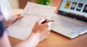 Comment passer à la dématérialisation des factures en 5 étapes ? Employée scannant des factures papier devant écran de gestion numérique